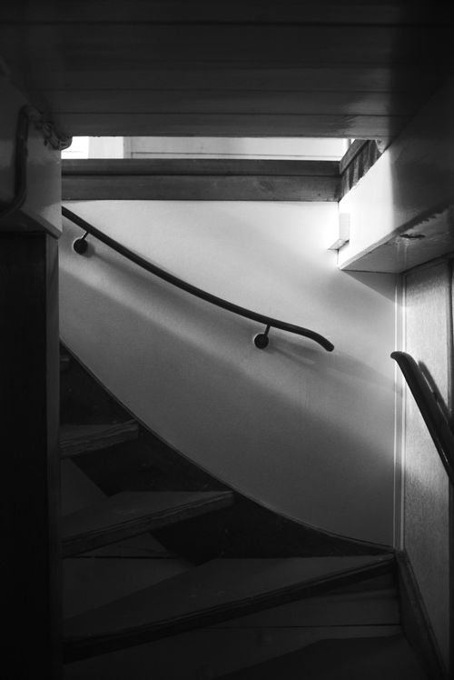 Free Black and white image of a spiral staircase with a curved handrail in indoor lighting. Stock Photo