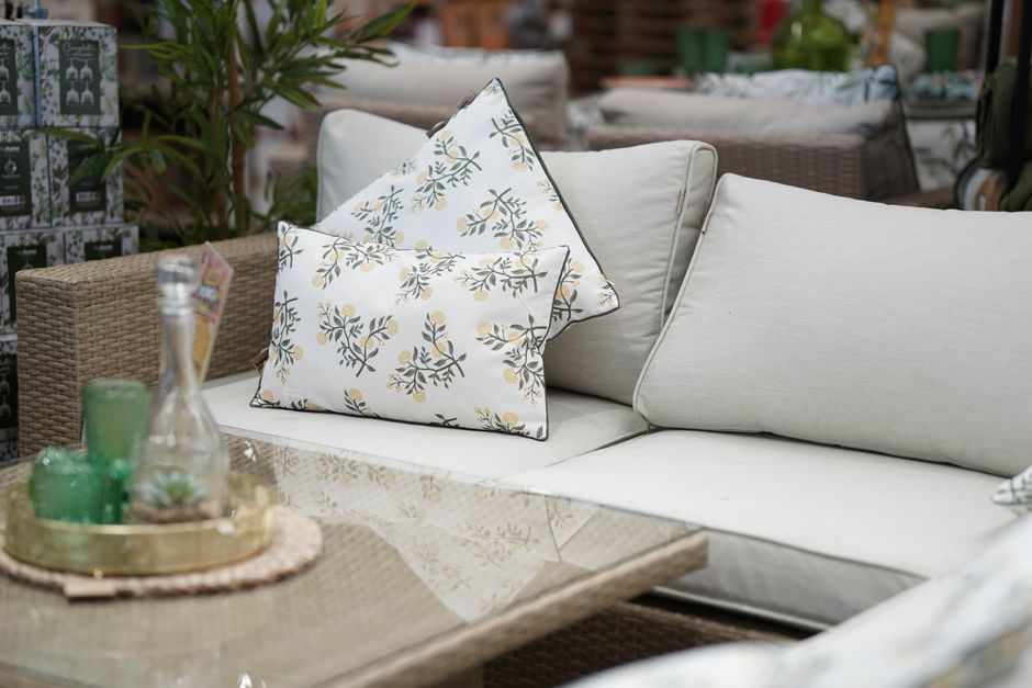 Cozy outdoor patio setting featuring stylish floral-patterned cushions on a wicker sofa and glass table.