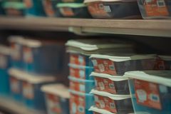 Rows of neatly stacked food containers in various colors on store shelves.