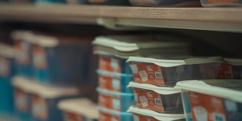 Rows of neatly stacked food containers in various colors on store shelves.