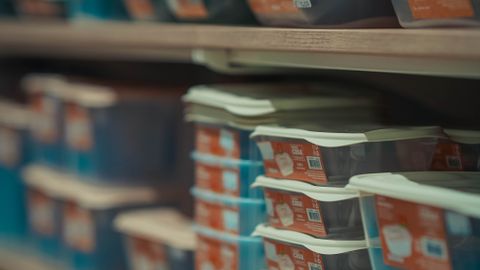 Rows of neatly stacked food containers in various colors on store shelves.