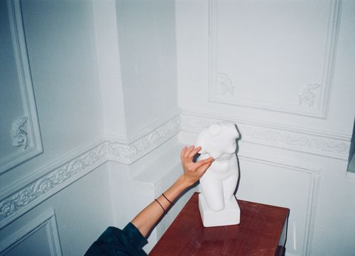 Free A hand delicately touches a classical sculpture in a minimalist interior, highlighting the blend of art and modernity. Stock Photo