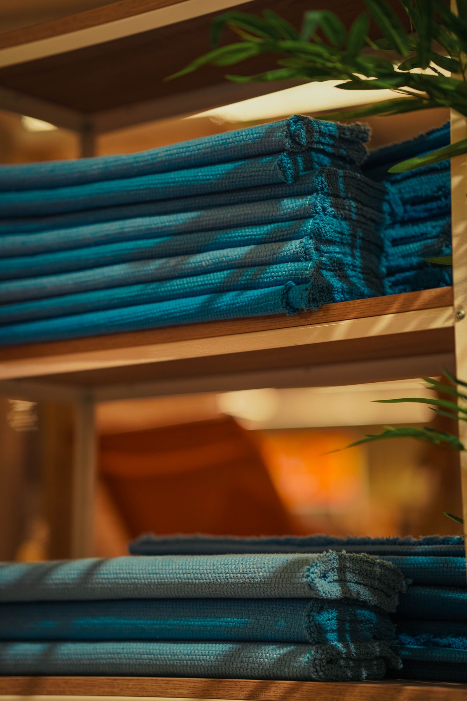 A neatly folded stack of tea towels arranged on a wooden kitchen shelf