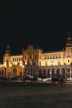 Illuminated Plaza de España at night in Seville, Spain showcasing stunning architecture.