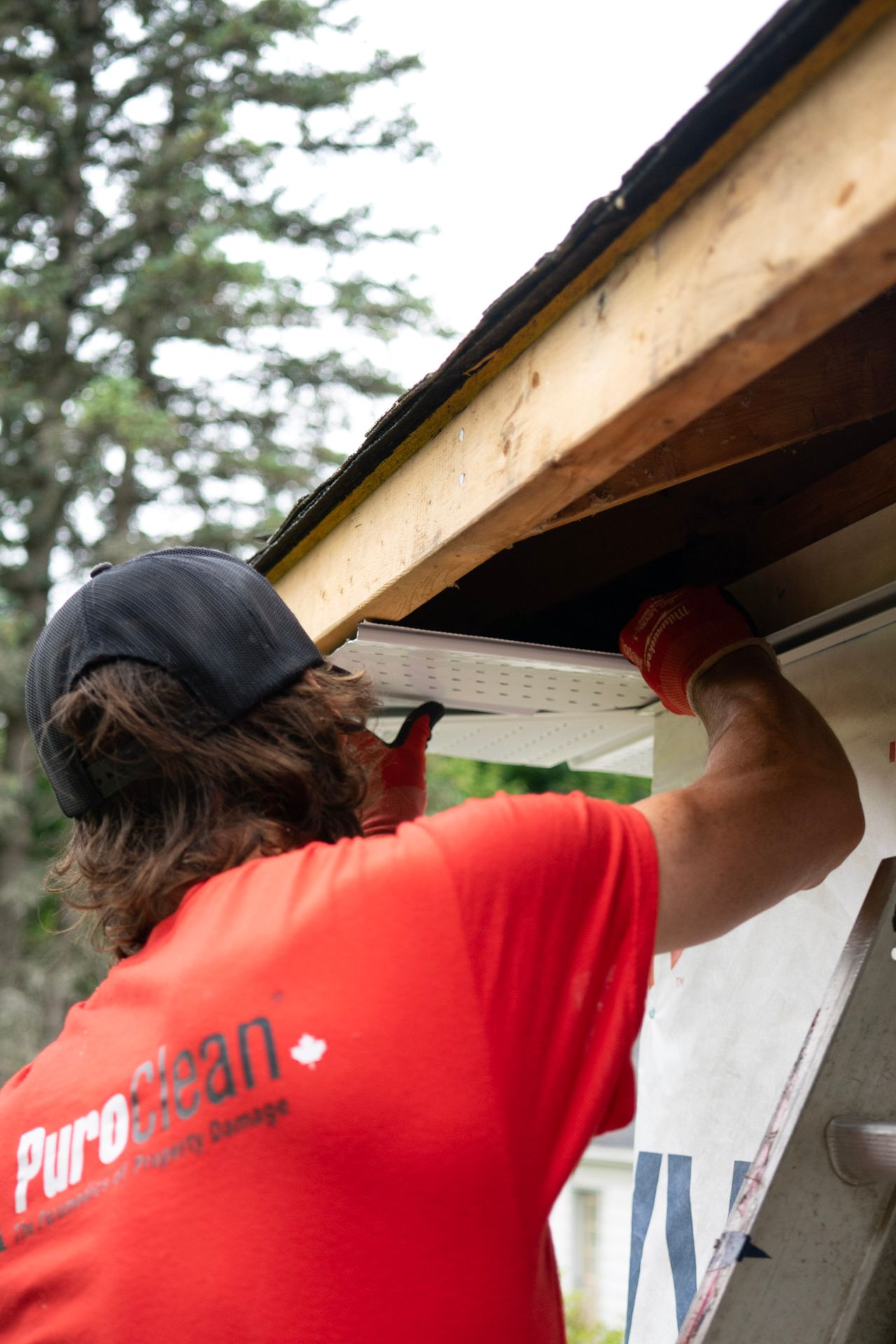 Gutter technician working along a residential roofline