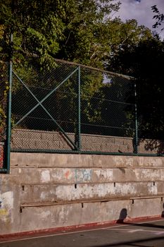 A sports court with fenced enclosure and concrete seating under the bright sky in Istanbul.
