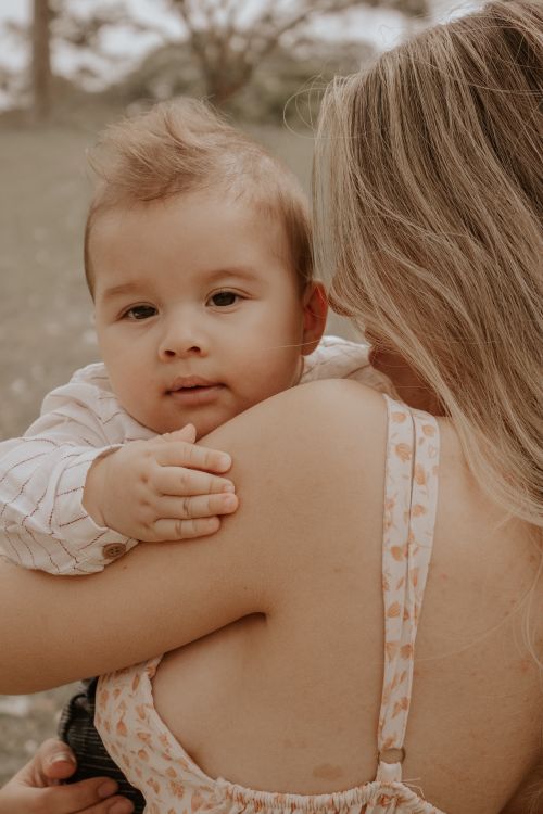 Free A mother lovingly holding her baby outdoors, depicting warmth and bonding. Stock Photo