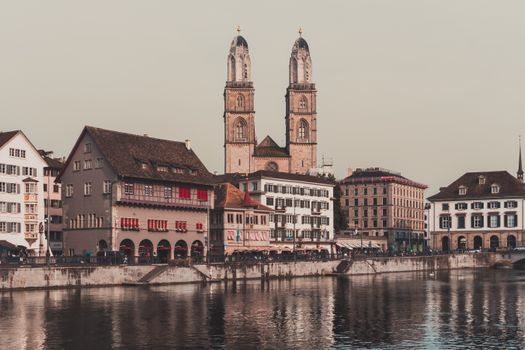 Capture of Zürich's historic Grossmünster Cathedral and riverside architecture reflecting on the water.