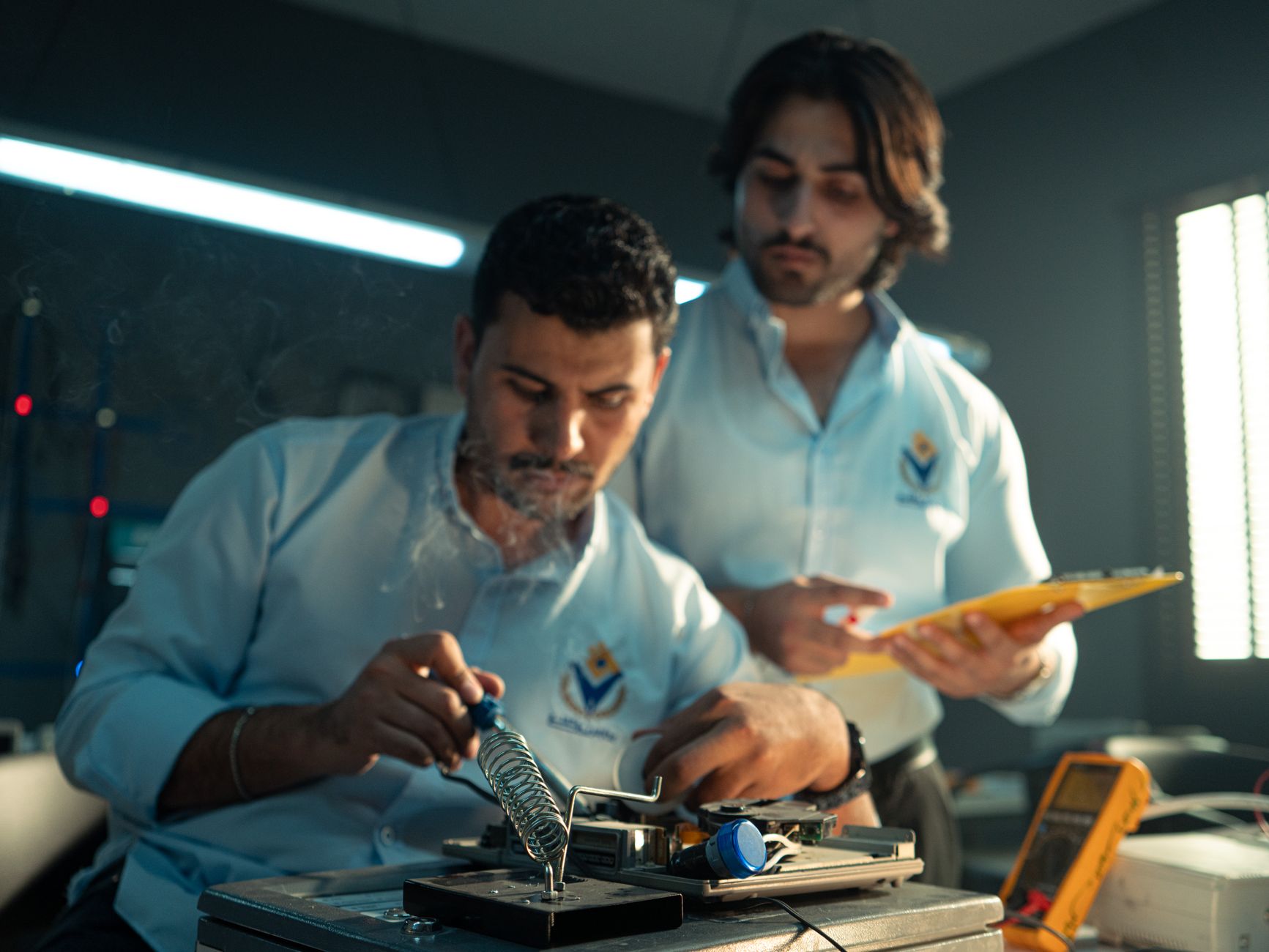 Two engineers focused on electronics assembly in a workshop in Baghdad, Iraq.