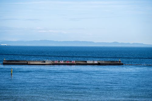 Free Scenic ocean view featuring concrete barriers, distant mountains, and a clear blue sky. Stock Photo
