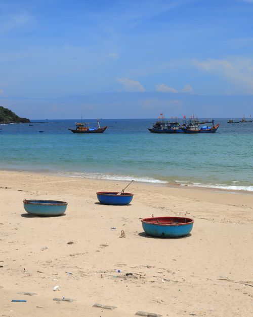 Free Peaceful scene of circular fishing boats on a sunny beach with vibrant blue skies. Stock Photo