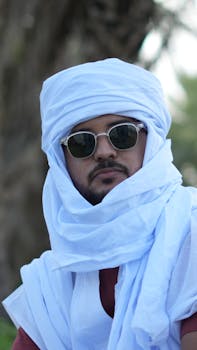 A man wearing a white turban and sunglasses outdoors, capturing cultural essence.