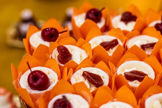 Close-up of cupcakes with cherries and vibrant orange wrappers, perfect for celebrations.