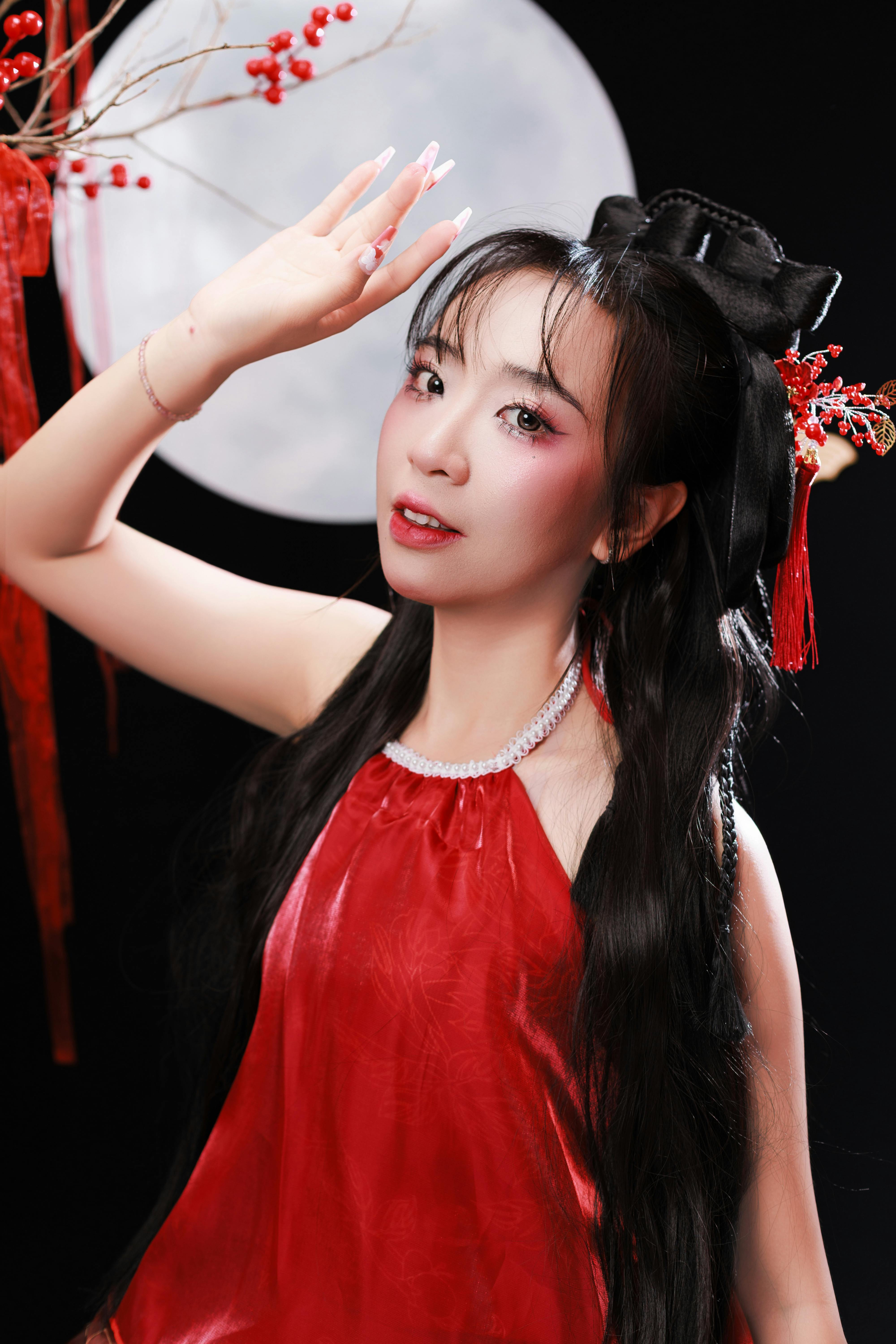 Portrait of a woman in a red dress holding a traditional pose in moonlight.
