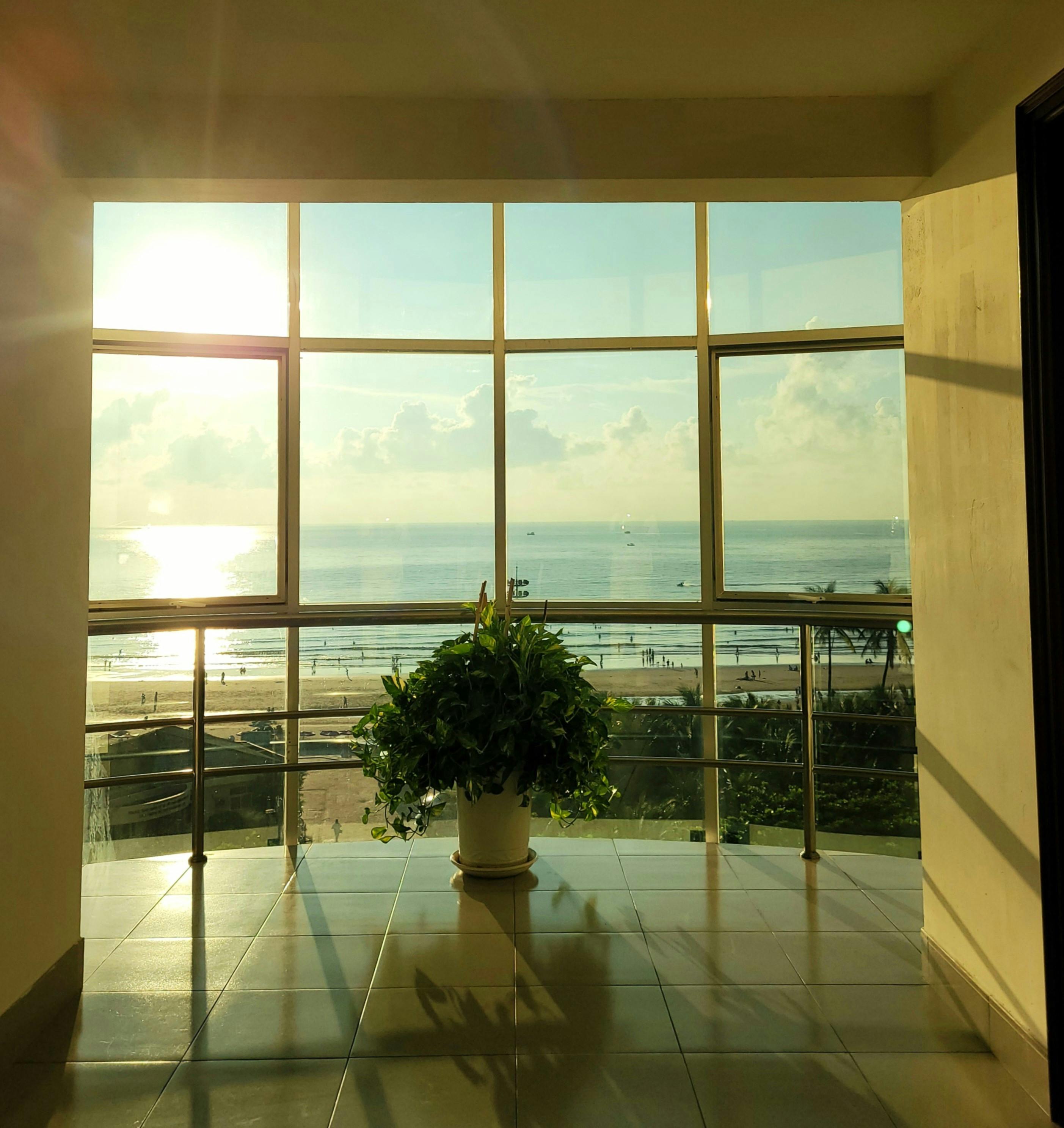 Bright sunlight illuminates a modern interior with a beach view from a balcony window.