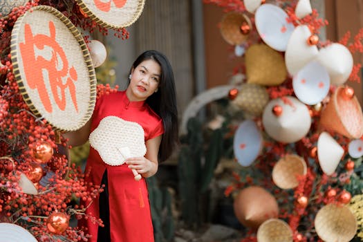 Woman in red dress posing with traditional Asian decorations, showcasing festive elements with vibrant colors.