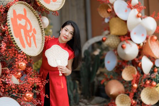 Woman in traditional red Ao Dai amidst vibrant decorations celebrating Lunar New Year.