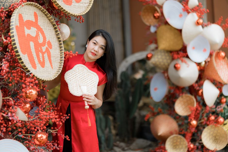 Woman in traditional red Ao Dai amidst vibrant decorations celebrating Lunar New Year.