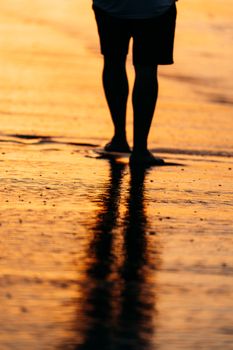 A serene silhouette of a person walking along the beach during a stunning sunset in El Salvador.