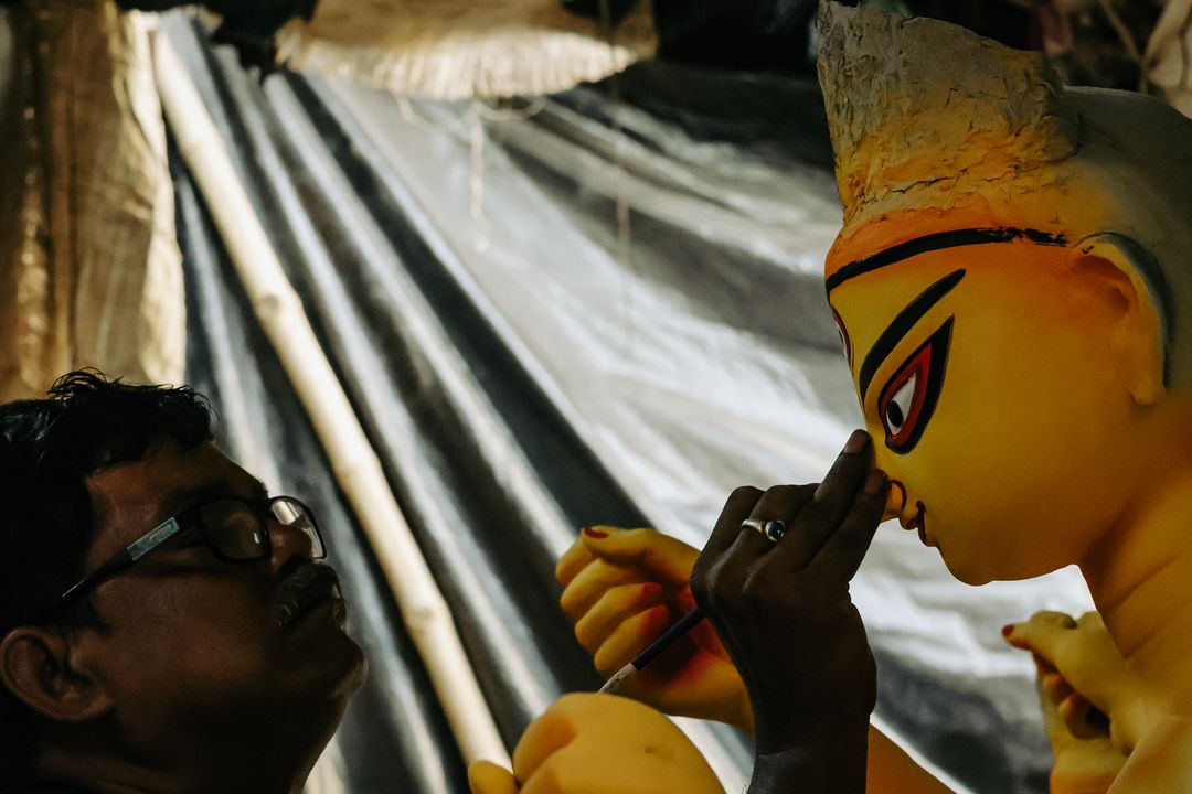 Artisan painting a Durga idol's face in Kumartuli