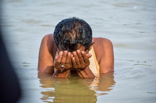 Free A man performs a sacred Hindu ritual in the Ganga River, Kolkata, symbolizing spirituality and tradition. Stock Photo