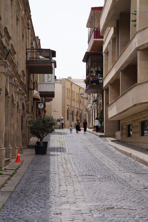Free A picturesque cobblestone street in a historic old town with people strolling. Ideal for travel enthusiasts. Stock Photo