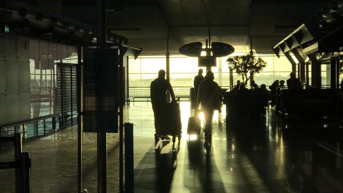 Travelers moving through a sunlit airport terminal before European border control