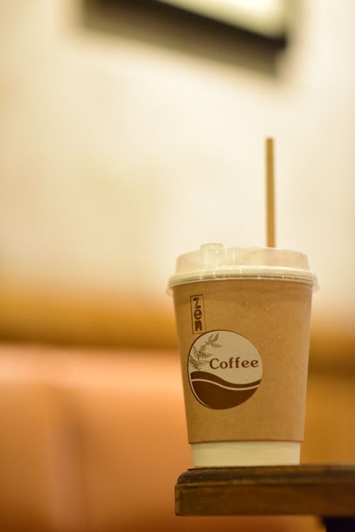 Free A brown eco-friendly coffee cup with a straw on a wooden table indoors. Stock Photo