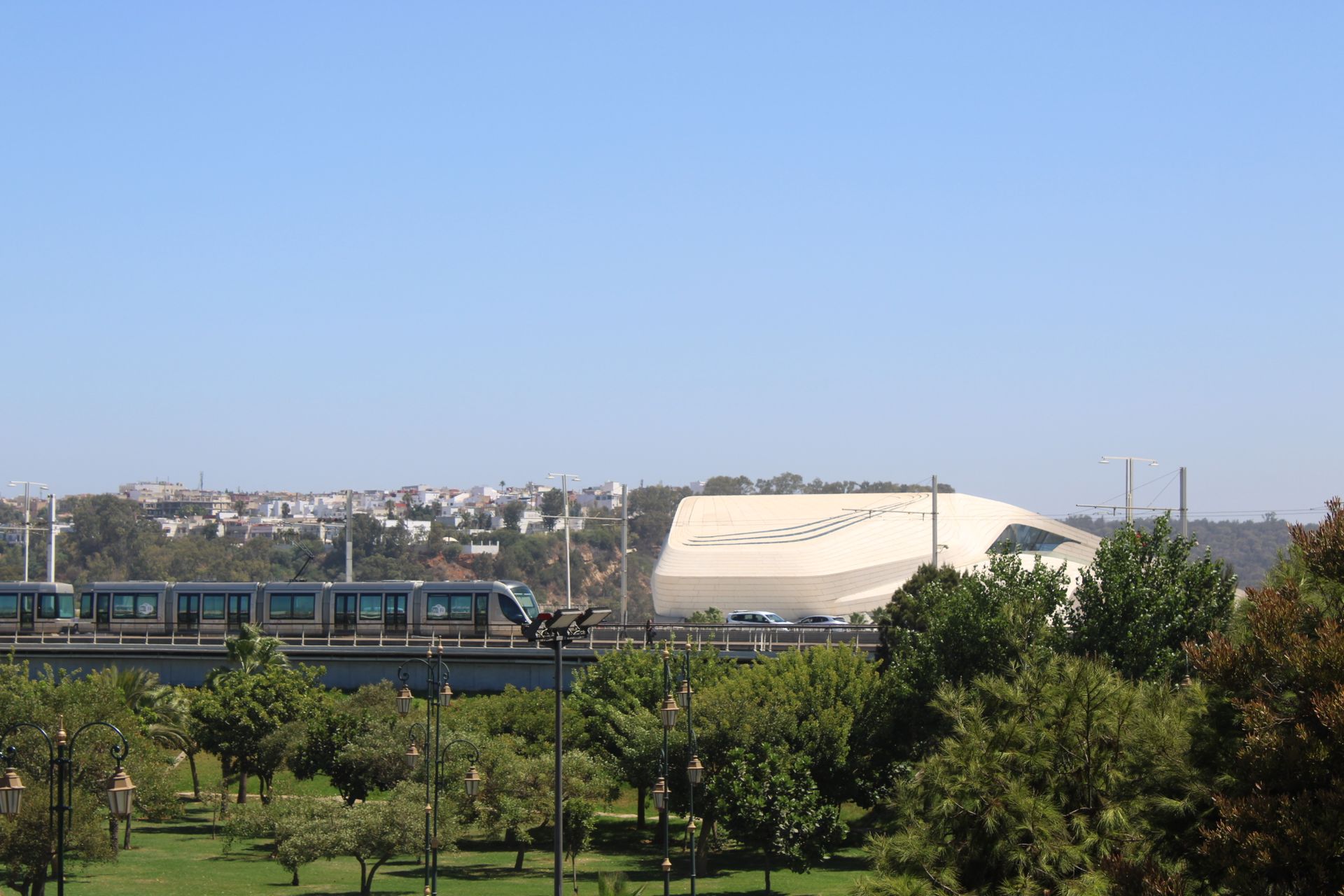 A tram crosses a bridge with modern architecture in Rabat, Morocco under a clear blue sky.