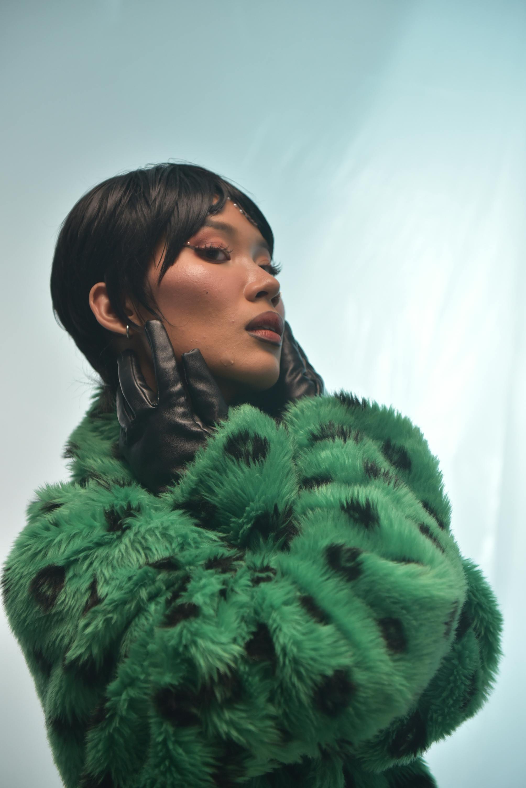 Free Stylish portrait of a woman in a green fur coat with gloves, exuding elegance. Stock Photo
