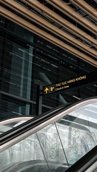 Modern airport interior with escalator and check-in area sign at Ho Chi Minh City, Vietnam.