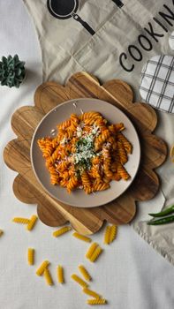 A high-angle shot of rotini pasta in tomato sauce garnished with herbs and cheese, perfect for meal inspiration.