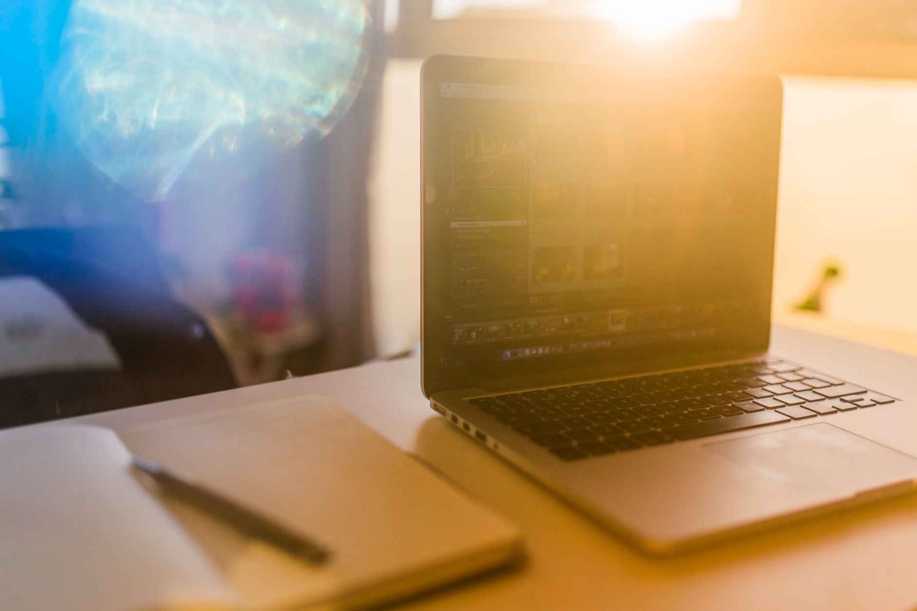 書桌面反光怎麼辦?材質選擇與擺位全解方 A laptop and notebook on a sunlit desk create a warm workspace vibe.