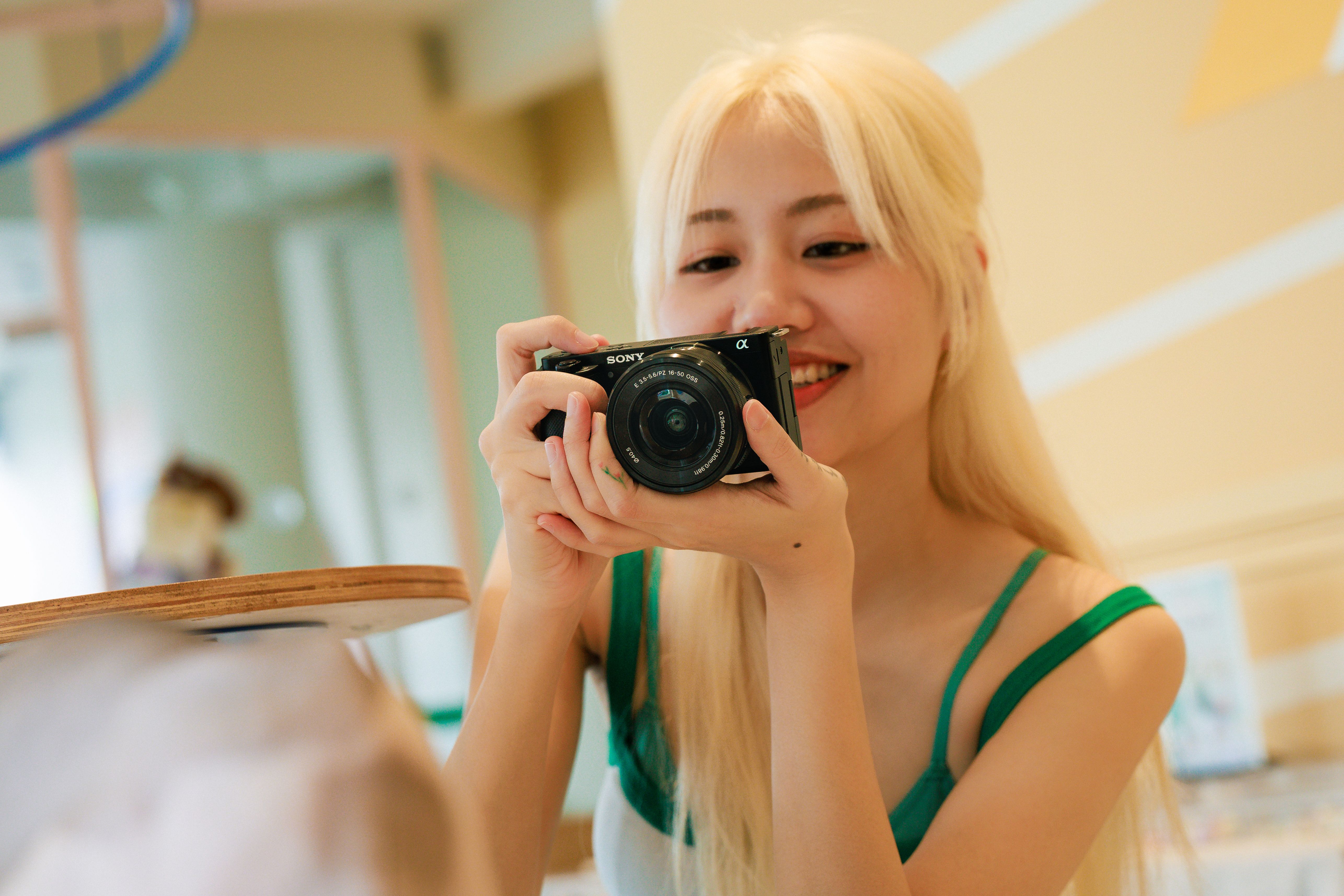 Smiling young woman using a camera indoors, capturing a candid moment.