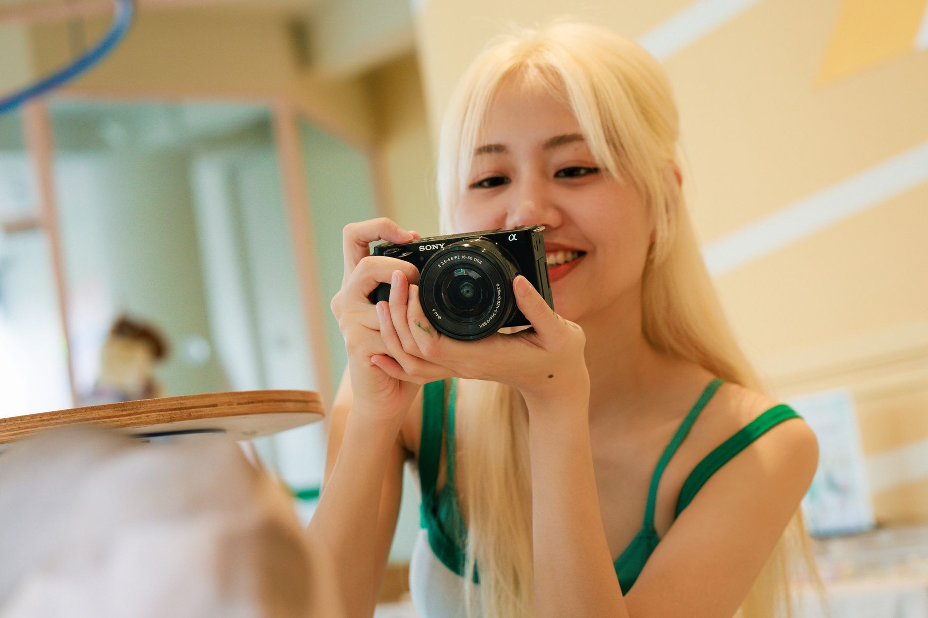 Smiling young woman using a camera indoors, capturing a candid moment.