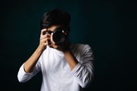 Portrait of a young photographer in a studio setting holding a camera.