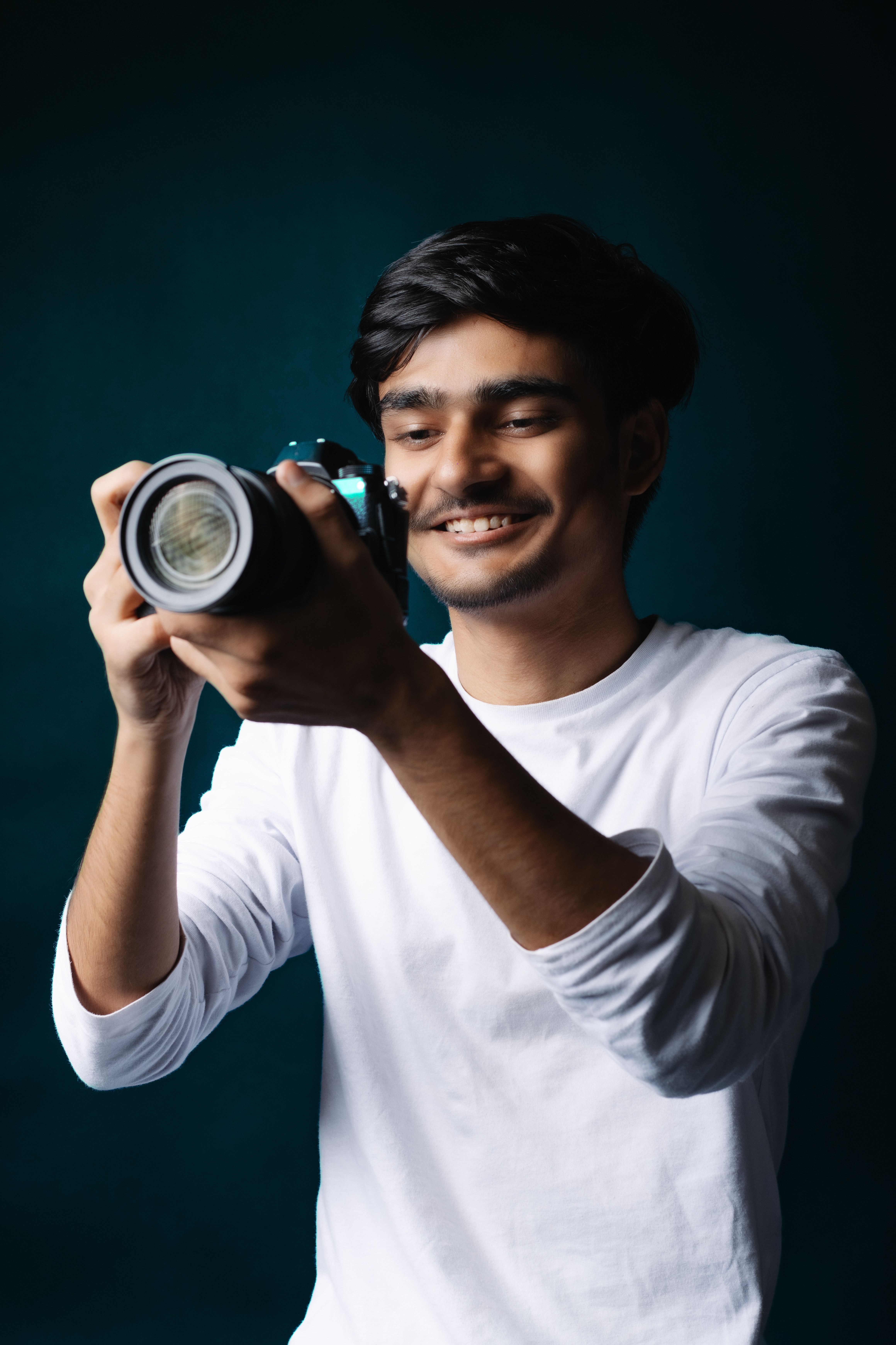 Smiling young man with a camera taking a photo in a creative studio setting.