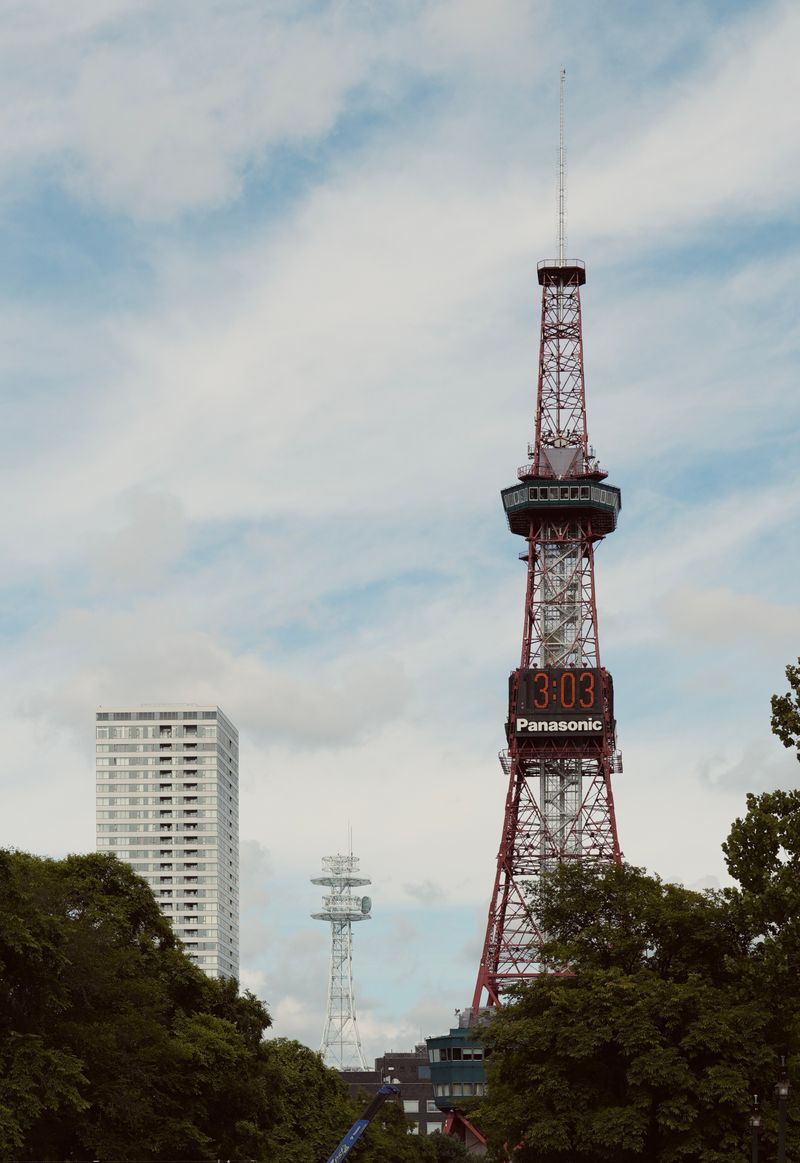 Sapporo TV Tower against a cloudy sky above Odori Park