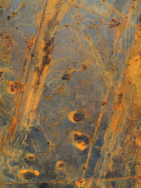 Close-up of rust on metal showing abstract patterns and textures in earthy tones.