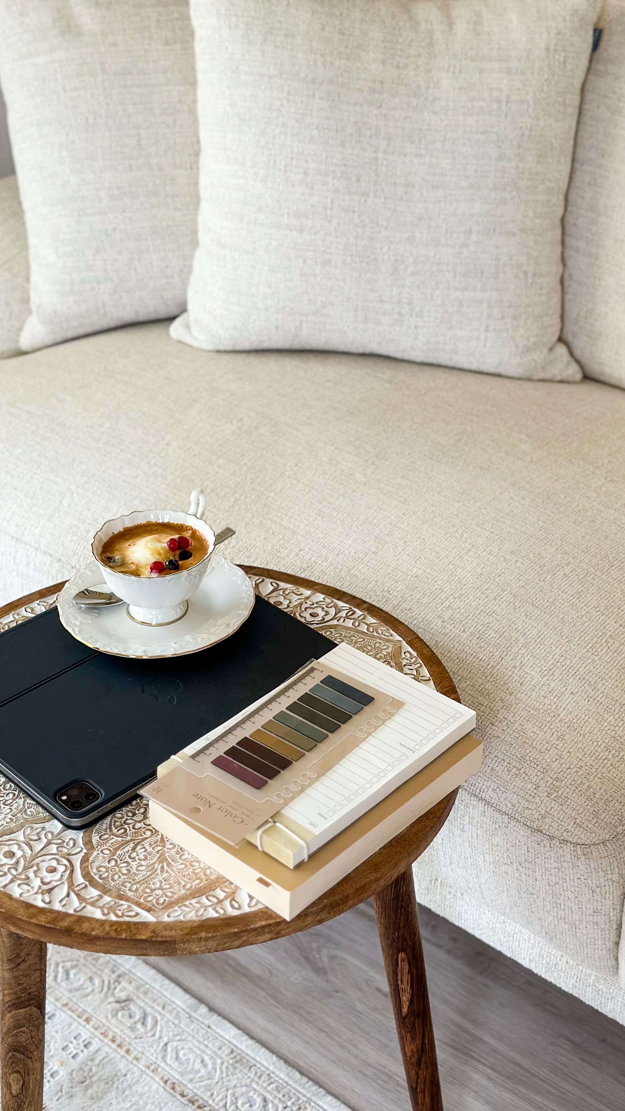 Inviting living room scene with coffee, tablet, and swatches on an ornate round table.