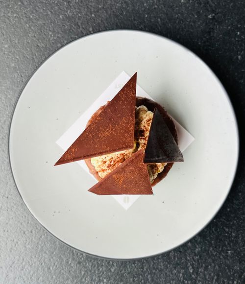 Free Top view of an artistic chocolate dessert with cream and cocoa triangles. Stock Photo