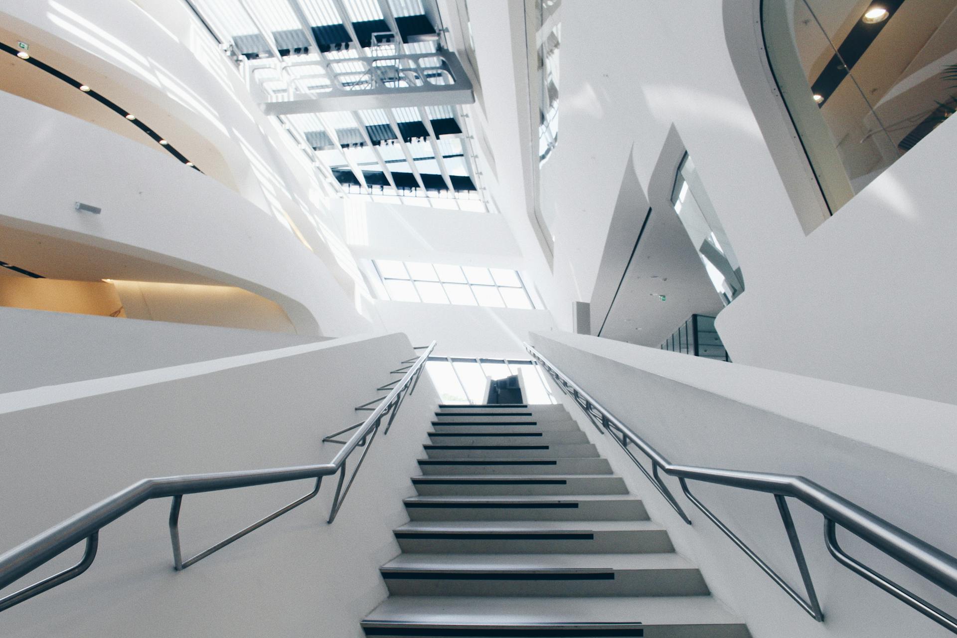 Low angle view of a sleek, modern staircase with glass skylights in a futuristic architectural space.