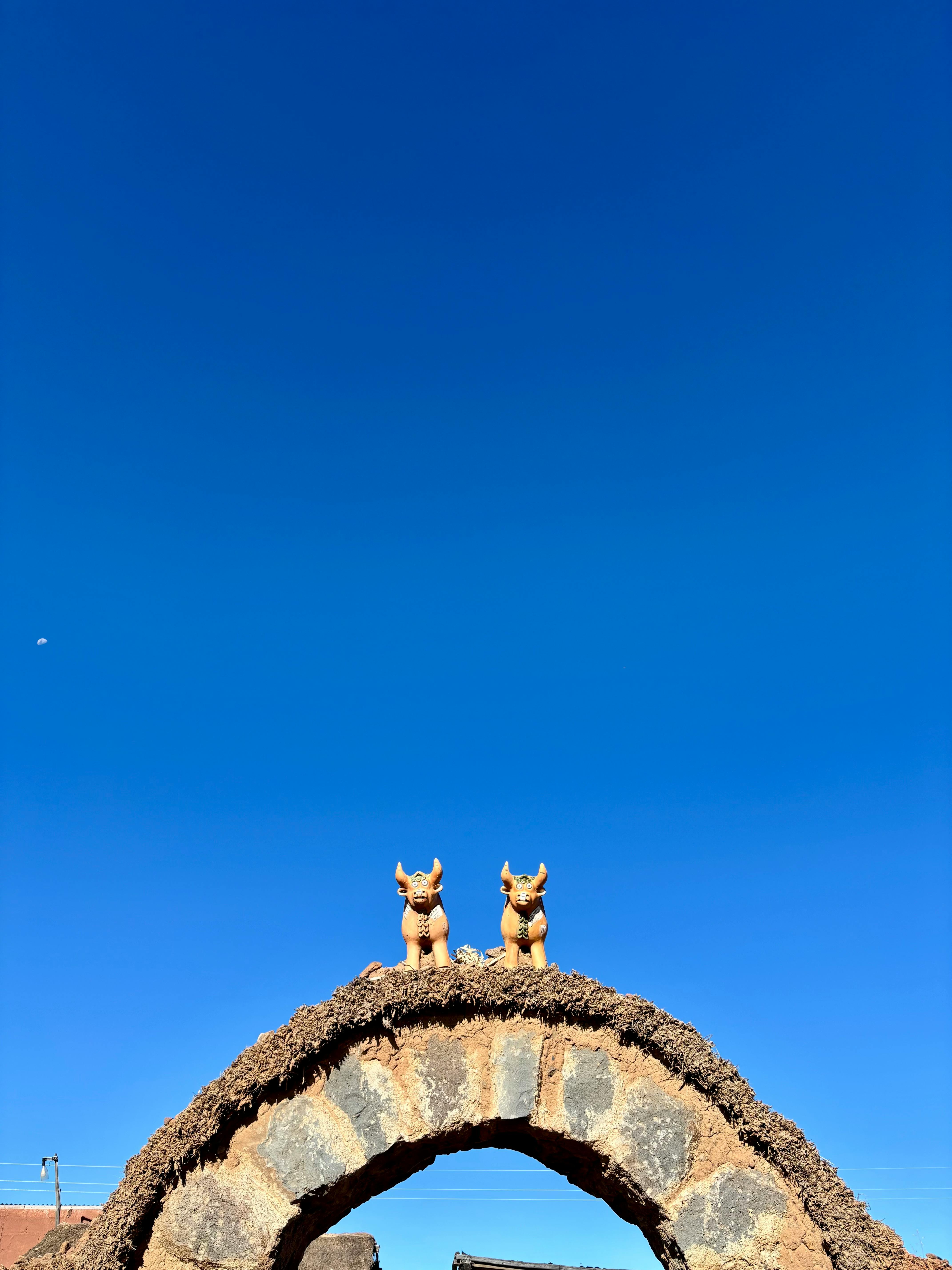 grátis Arco tradicional com figuras de Touro sob um céu azul vibrante na Ilha Taquile, no Lago Titicaca. Foto profissional