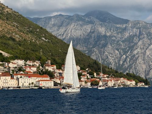 Free Scenic view of a sailboat near Kotor with dramatic mountain backdrop. Stock Photo