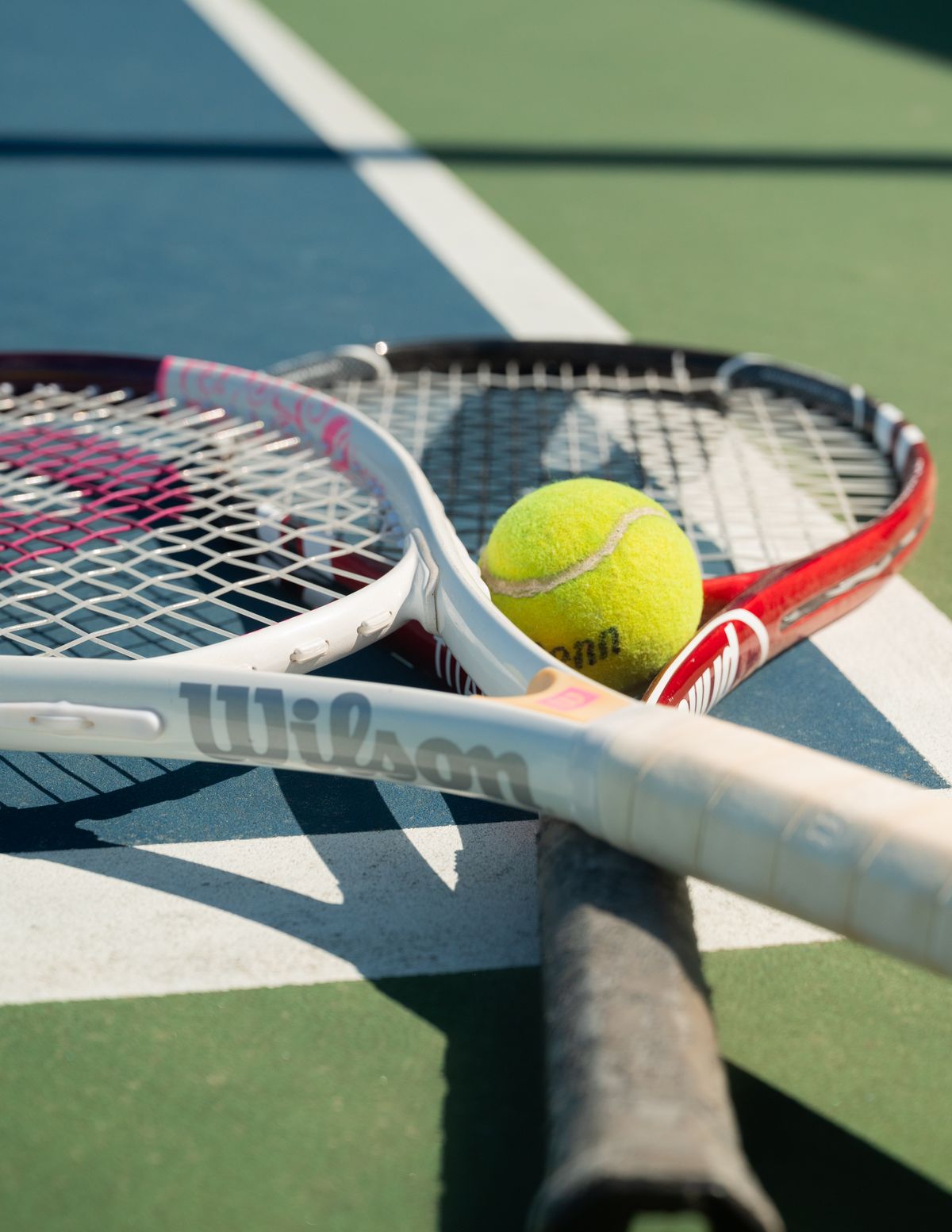 Tennis rackets and a ball resting on a tennis court