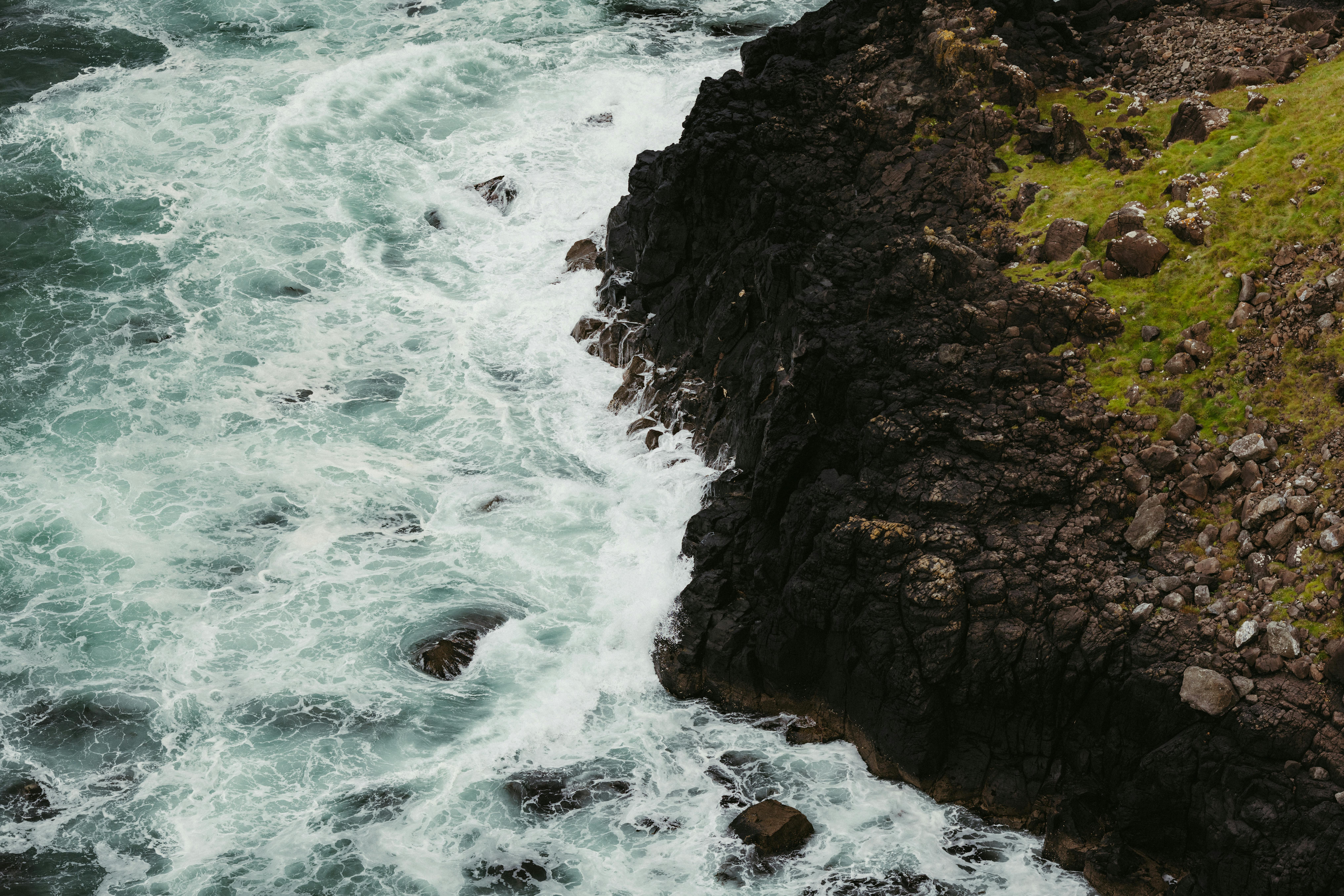 Aerial view of the rugged coastline in Northern Ireland with crashing waves and rocky cliffs.