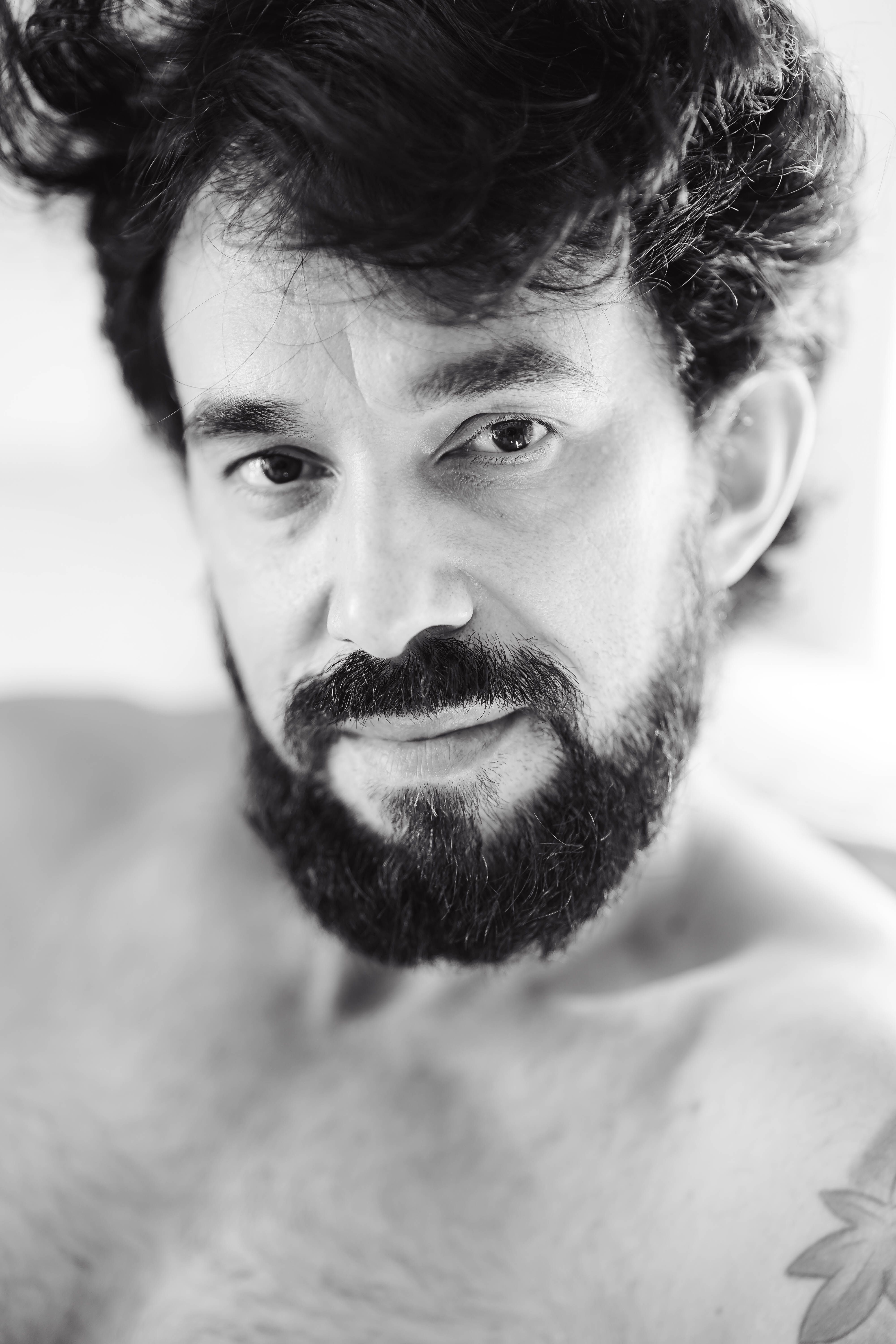 Close-up black and white portrait of a bearded man with soft focus background.