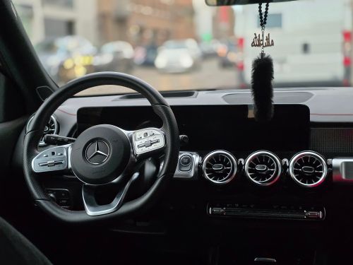 Free Elegant car interior featuring a luxury brand steering wheel and modern dashboard. Stock Photo