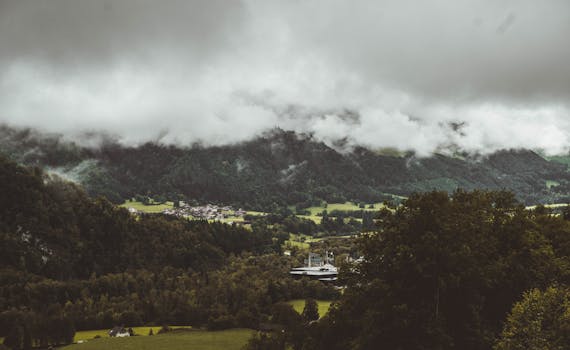 Dramatic cloud cover over lush green mountains in Gruyères, Switzerland.