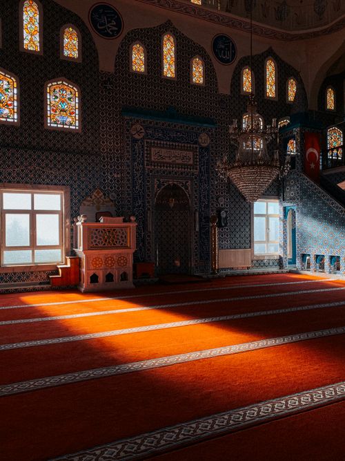 Free Sunlit interior of a beautifully adorned mosque featuring intricate tile work and stained glass windows. Stock Photo
